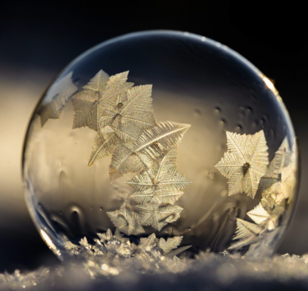 Close up of bubble containing snowflakes in a snow covered ground.